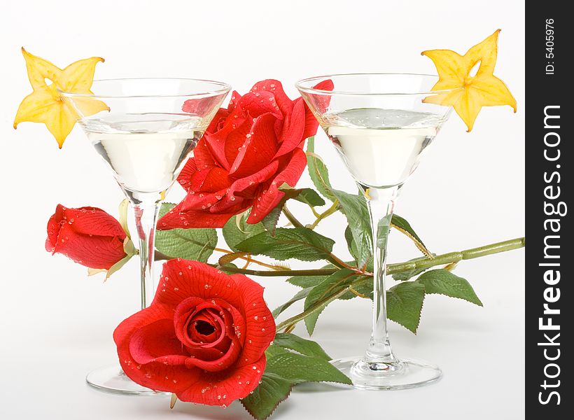 Two glasses of martini, red rose and slice of carambola on a white background. Two glasses of martini, red rose and slice of carambola on a white background