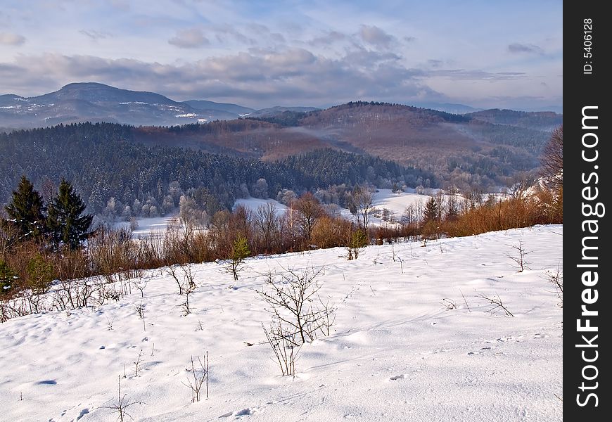 Winter landscape with snow covered ground and distant mountains