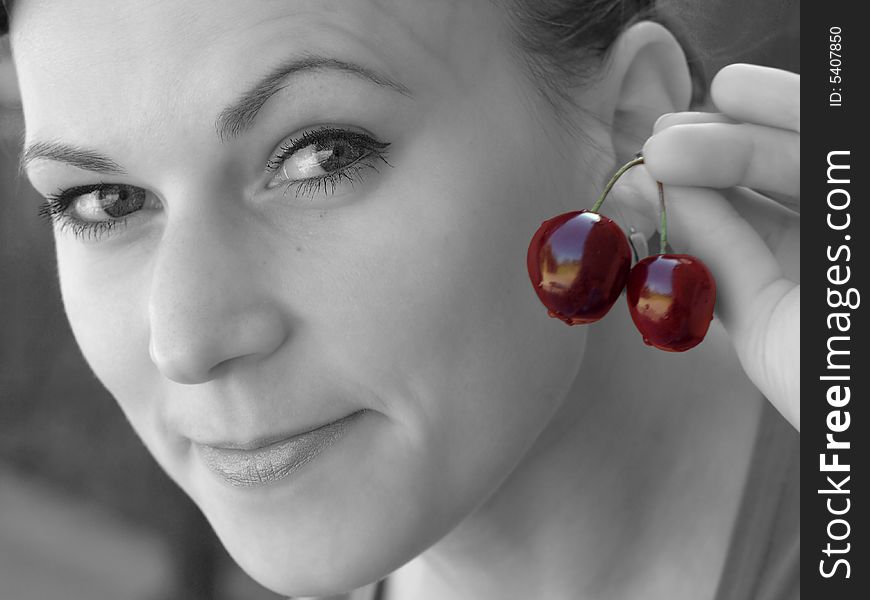 Young girl in black and white with colourful cherry in her fingers. Young girl in black and white with colourful cherry in her fingers