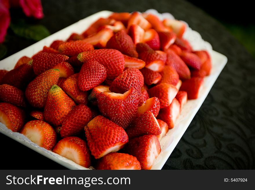 An appetizer plate of strawberries on a white plate with dark background