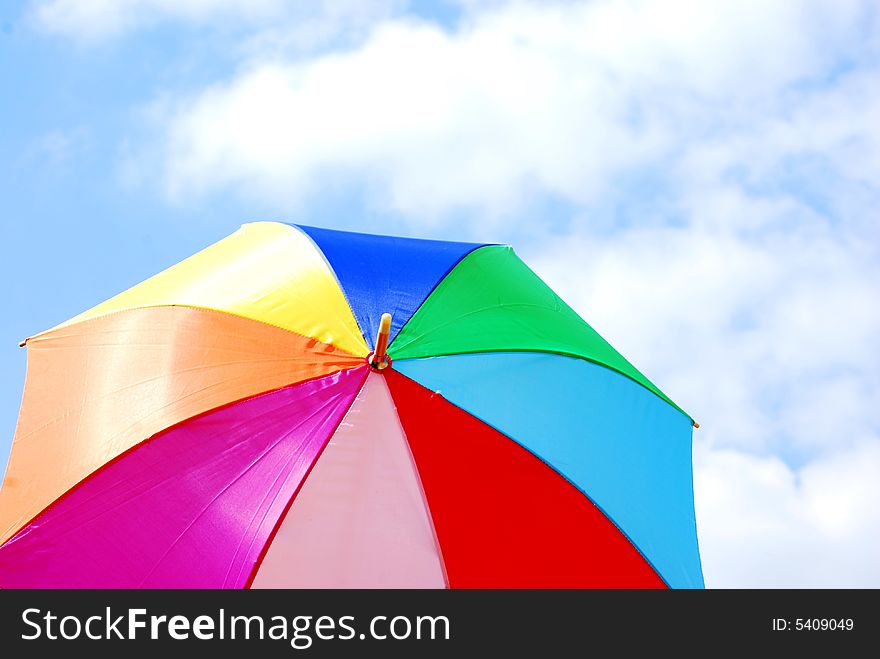 Shot of a colourful umbrella against a lovely blue sky