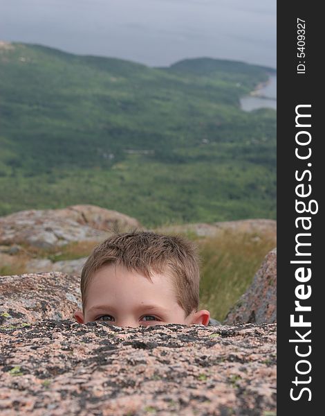 Child peeking over a rock at Acadia National Park