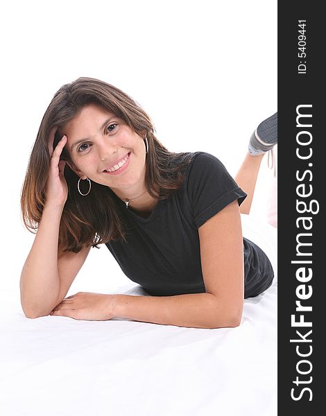 Pretty smiling teenage girl lying on her stomach with one hand in her hair. Pretty smiling teenage girl lying on her stomach with one hand in her hair.