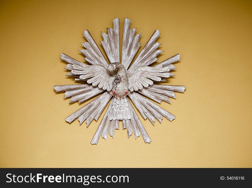 Religious symbol handmade wooden dove holy spirit on a yellow background. Religious symbol handmade wooden dove holy spirit on a yellow background