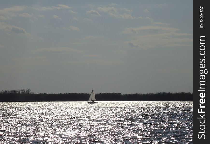 Sailboat floats alone on vast expanses of the river. Sailboat floats alone on vast expanses of the river.