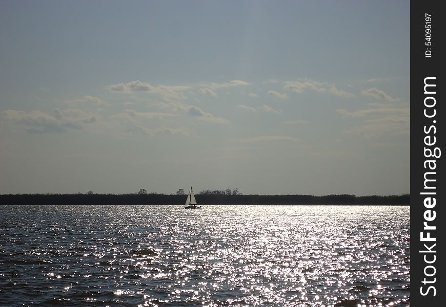 Sailboat floats alone on vast expanses of the river. Sailboat floats alone on vast expanses of the river.