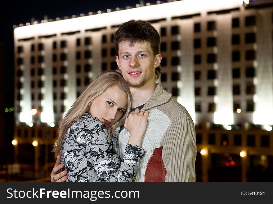 Young man and young woman staying on the bridge against night building. Young man and young woman staying on the bridge against night building