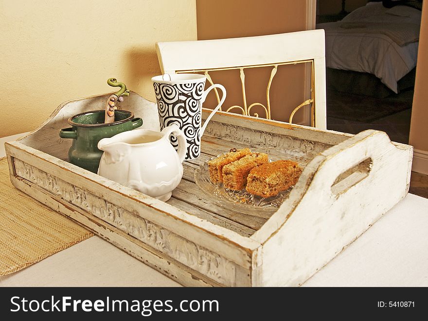 White French provincial tray with bran rusks , coffee cup, milkjar an sugerpot on table with chair. White French provincial tray with bran rusks , coffee cup, milkjar an sugerpot on table with chair