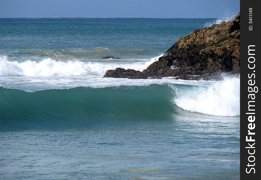 Green wave curling perfectly with rocks in the background