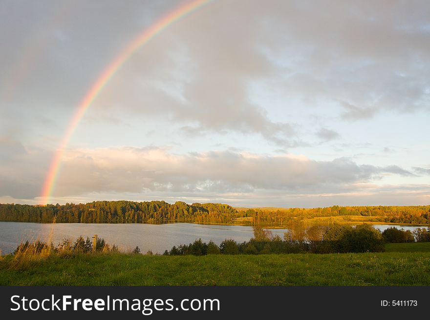 The cloudy sky and autumn rainbow above lake