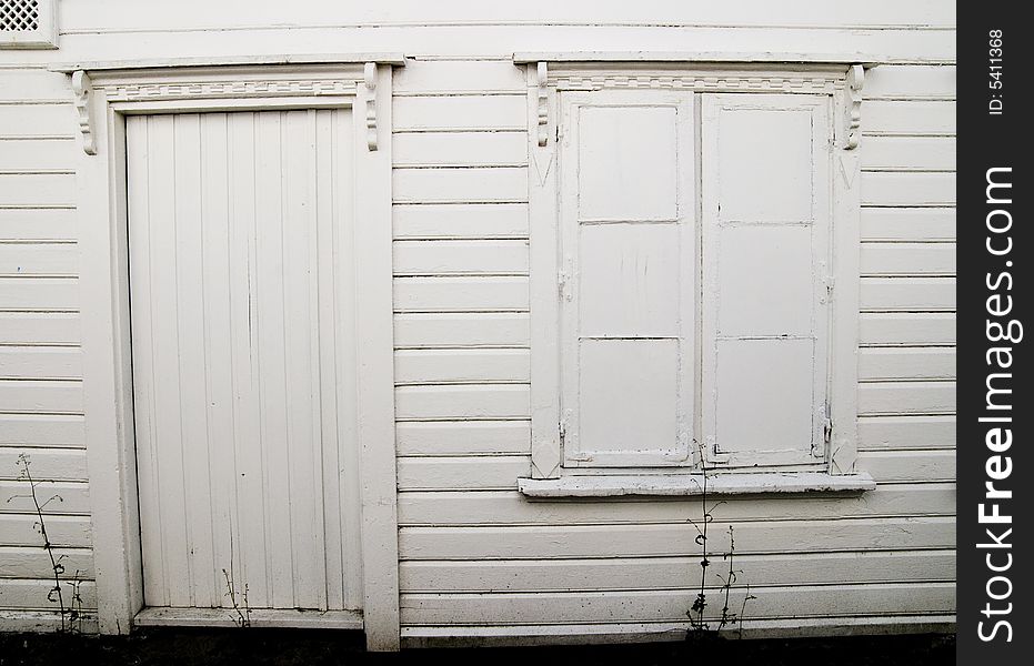 Wall of an white house with painted window and missing door handle. Wall of an white house with painted window and missing door handle.