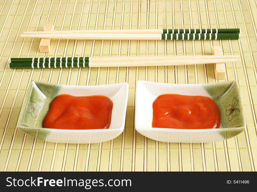Set of chopsticks and sauce plates on a mat. Set of chopsticks and sauce plates on a mat