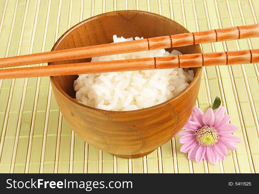 Wooden bowl of white rice and chopsticks