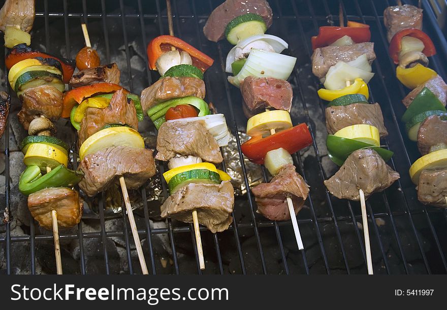 Several Shishkabobs on a grill