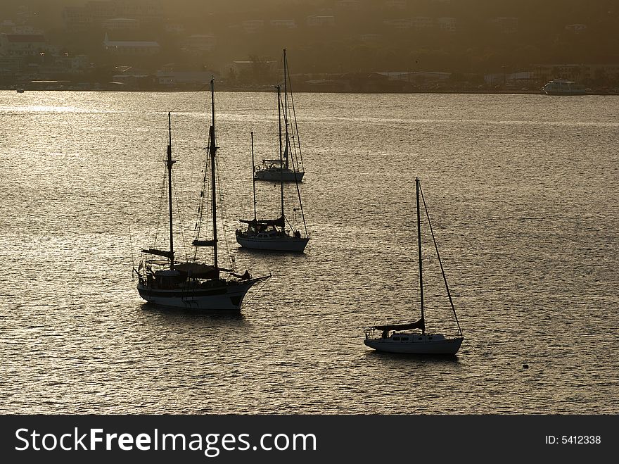 Yachts filled with sunset light are anchored in St.Thomas island bay, U.S. Virgin Islands. Yachts filled with sunset light are anchored in St.Thomas island bay, U.S. Virgin Islands.