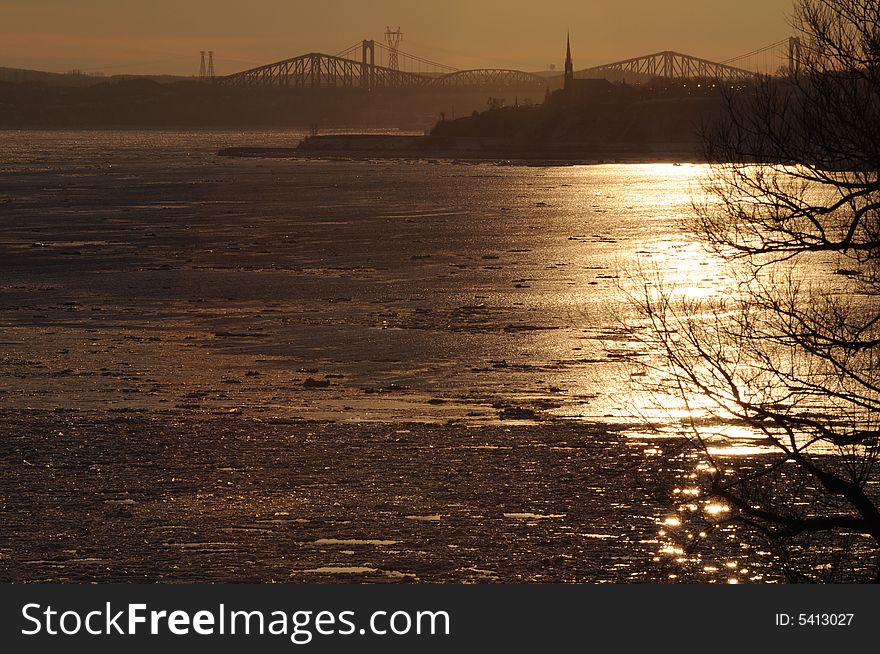 In winter, the sunset light, shining on the ice, often creates spectacular scenes on the Saint-Lawrence River. In the background we can see the old Quebec Bridge built 100 years ago. In winter, the sunset light, shining on the ice, often creates spectacular scenes on the Saint-Lawrence River. In the background we can see the old Quebec Bridge built 100 years ago.