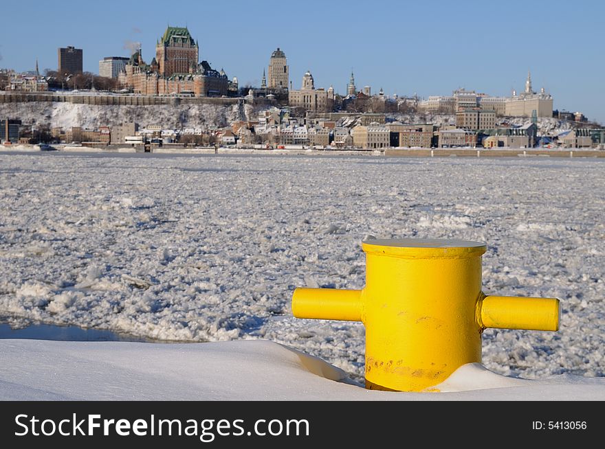 This yellow bollard seems very useless half buried in the snow. Facing the frozen Saint-Lawrence River, it waits quietly the spring to see ships coming to moor again. In the background we can see Quebec City. This yellow bollard seems very useless half buried in the snow. Facing the frozen Saint-Lawrence River, it waits quietly the spring to see ships coming to moor again. In the background we can see Quebec City.