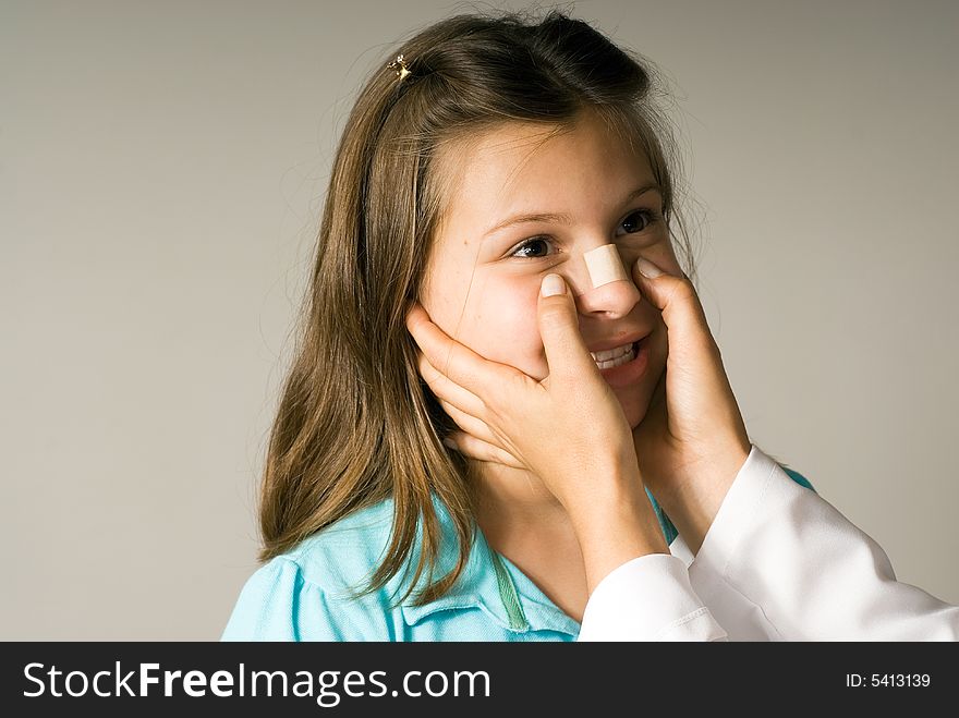 Young girl smiles while a band-aid is applied to her nose. She is happy to be taken care of. Horizontally framed photograph. Young girl smiles while a band-aid is applied to her nose. She is happy to be taken care of. Horizontally framed photograph