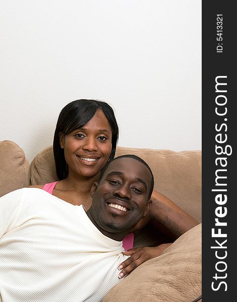 Happy, smiling, attractive couple on a couch. He is lying across her lap. Vertically framed photograph. Happy, smiling, attractive couple on a couch. He is lying across her lap. Vertically framed photograph.