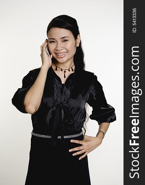 Smiling Asian woman using mobile phone, against white background. Smiling Asian woman using mobile phone, against white background