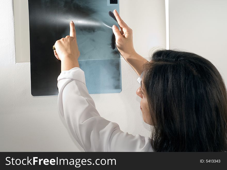 Female Doctor points to an x-ray. Horizontally framed photograph. Female Doctor points to an x-ray. Horizontally framed photograph