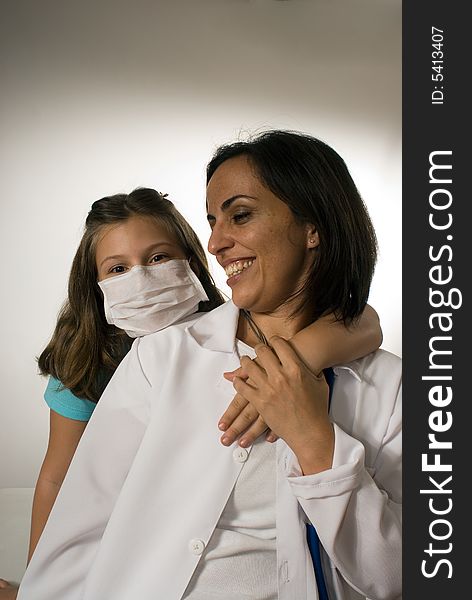 Young girl wearing a mask puts her arm lovingly around the doctor who looks at her playfully. They are playing around and being silly and enjoying each others company. Vertically framed photograph. Young girl wearing a mask puts her arm lovingly around the doctor who looks at her playfully. They are playing around and being silly and enjoying each others company. Vertically framed photograph