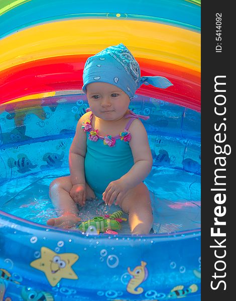 8 month old girl sitting in a small swimming pool. 8 month old girl sitting in a small swimming pool