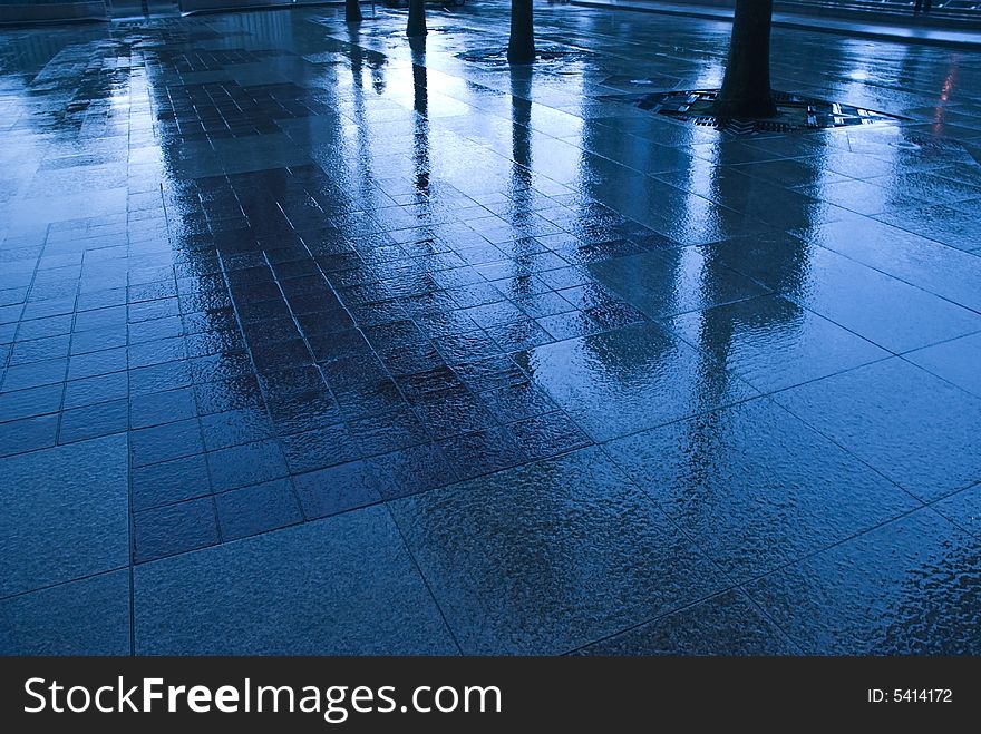 A blue filtered image of rain on a side walk. A blue filtered image of rain on a side walk