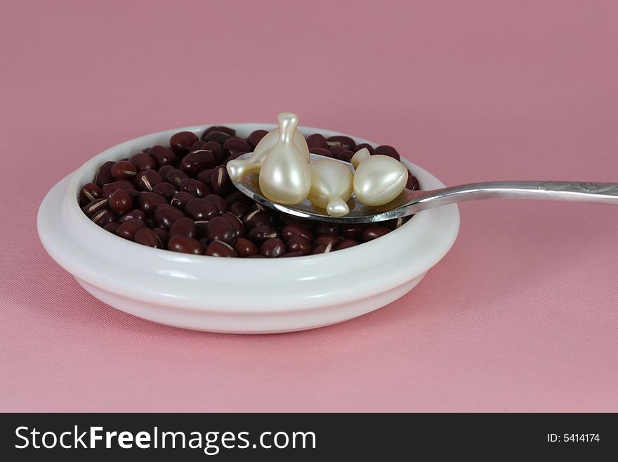 Beans in the spoon and cup on pink background. Beans in the spoon and cup on pink background