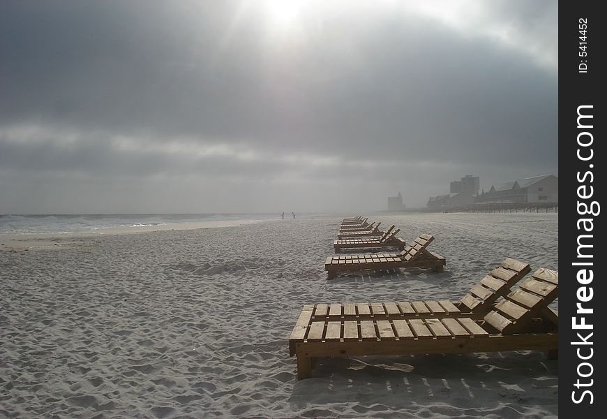 Beachchairs on Pensacola Beach lighted by the sun peeking through rain clouds