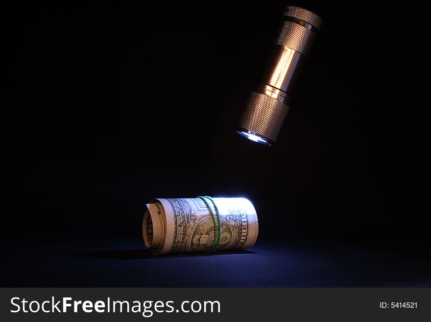 Lighting electric torch and roll of dollar banknotes on dark background. Lighting electric torch and roll of dollar banknotes on dark background