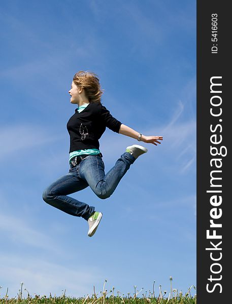 The young happy jumping girl on a background of the blue sky. The young happy jumping girl on a background of the blue sky