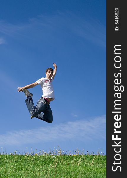 The young happy jumping guy on a background of the blue sky. The young happy jumping guy on a background of the blue sky