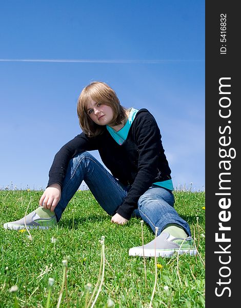 The Young Girl Sitting On A Green Grass