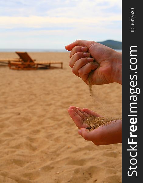 A young woman pouring sand from one hand into the other one. Beach shot with summer feeling. A young woman pouring sand from one hand into the other one. Beach shot with summer feeling.