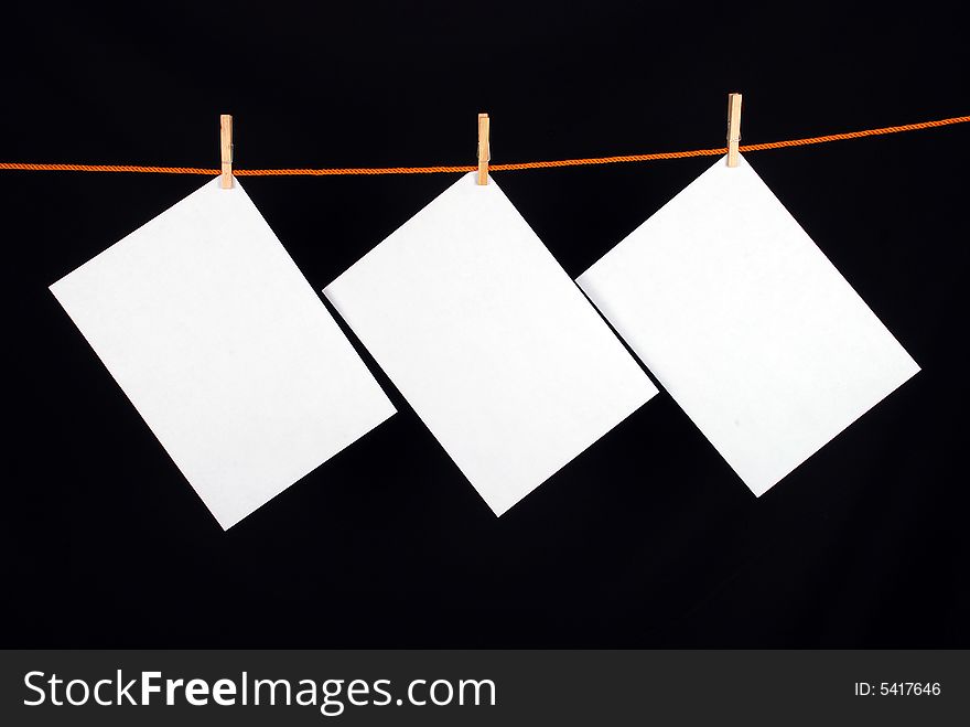 Three White papers with wooden clips on black background. Three White papers with wooden clips on black background