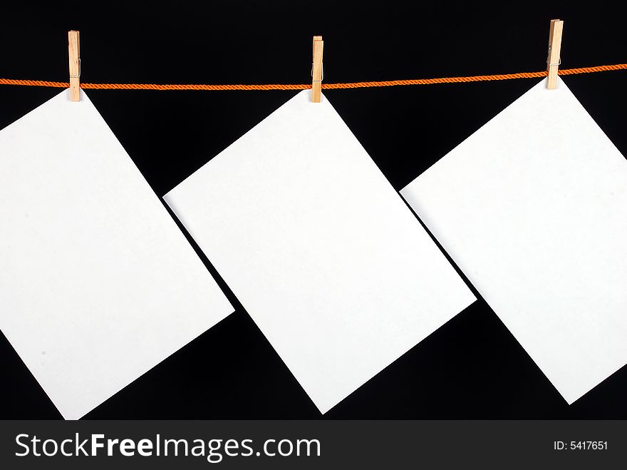 Three White papers with wooden clips on black background. Three White papers with wooden clips on black background