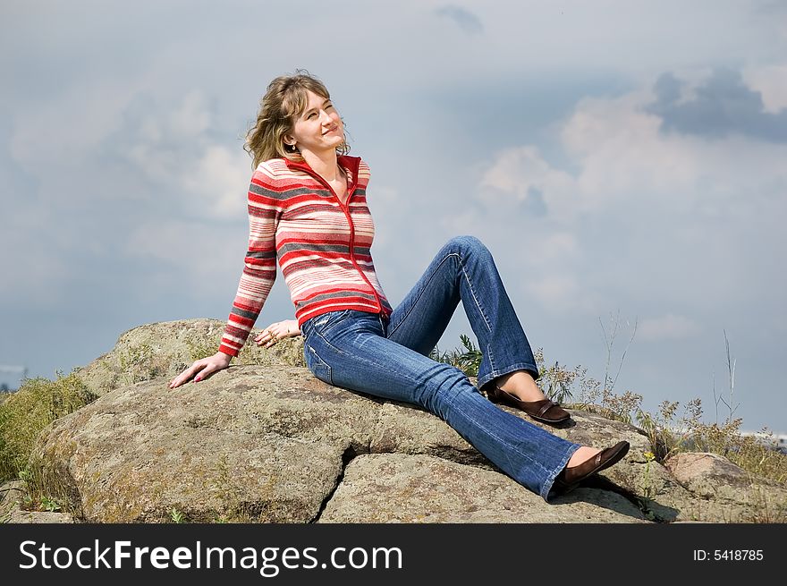 Girl sits on stones and looks in the sky. Girl sits on stones and looks in the sky