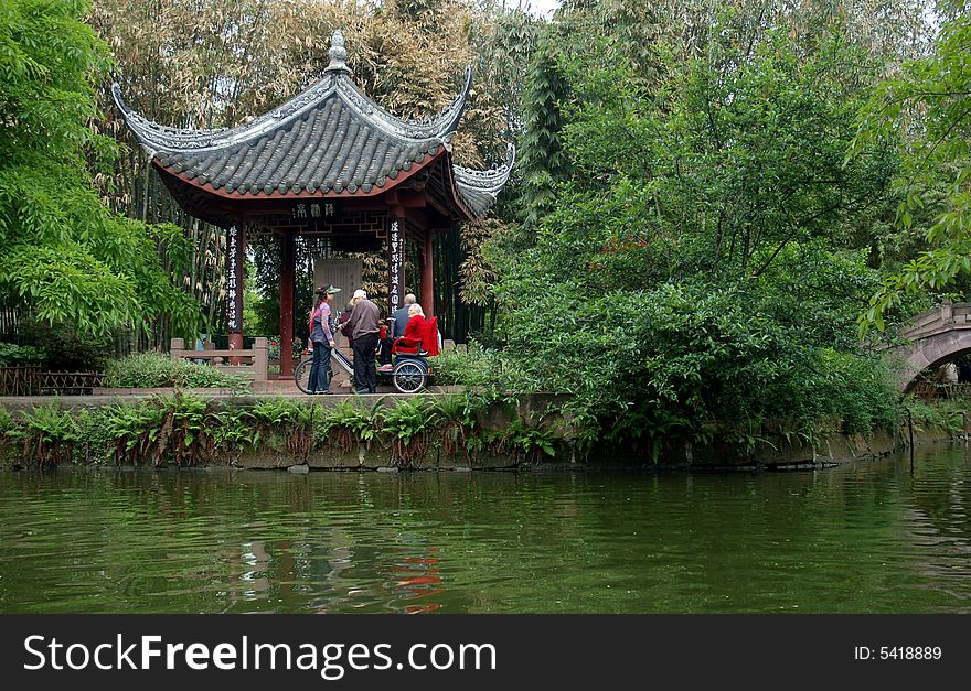 People in  a traditional garden by a lake in China.