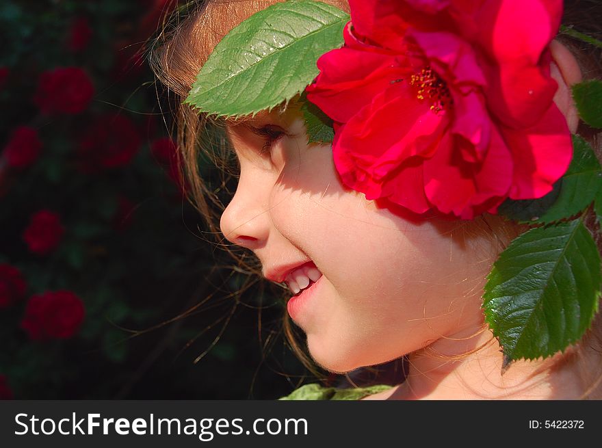 Beautiful little girl with a bright red rose in her hair. Beautiful little girl with a bright red rose in her hair