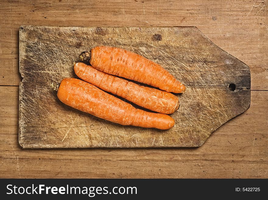 Three carrots on a cuttimg table, studio shot. Three carrots on a cuttimg table, studio shot.