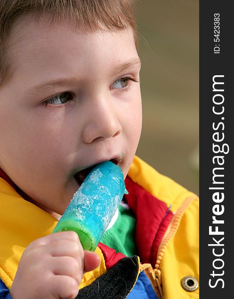 Young boy eating a blue popsicle. Young boy eating a blue popsicle.