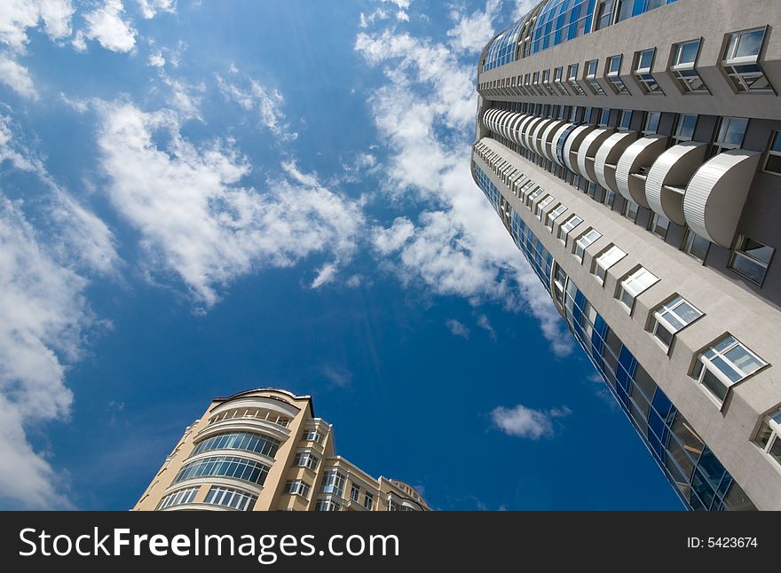 Tall office or residential building on blue sky with clouds. Wide-angle lens used. Tall office or residential building on blue sky with clouds. Wide-angle lens used.