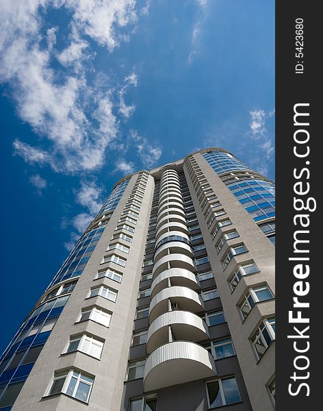 Tall office or residential building on blue sky with clouds. Wide-angle lens used. Tall office or residential building on blue sky with clouds. Wide-angle lens used.