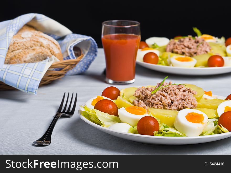 Salad with boiled potato, fish, egg, tomato and lettuce.