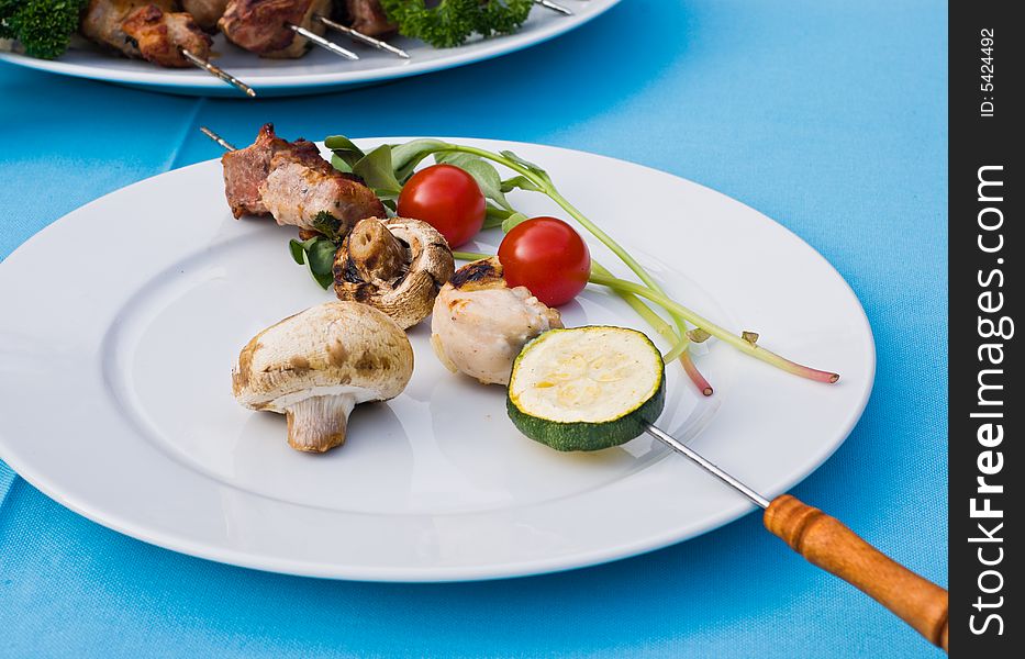Plate with a barbecue stick. Meat, mushrooms, vegetables. Plate with a barbecue stick. Meat, mushrooms, vegetables.