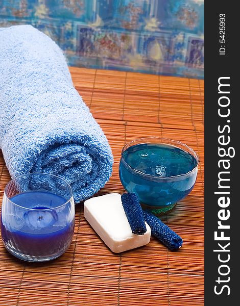 Spa scenery - blue towel, body oil, soap and candle