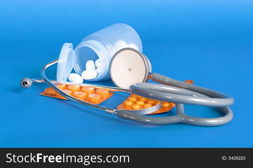 Stethoscope and pills on blue background. Stethoscope and pills on blue background