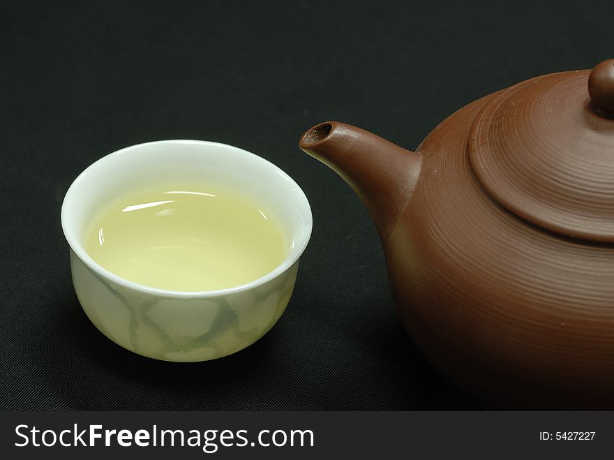 Isolated cup and teapot  on black