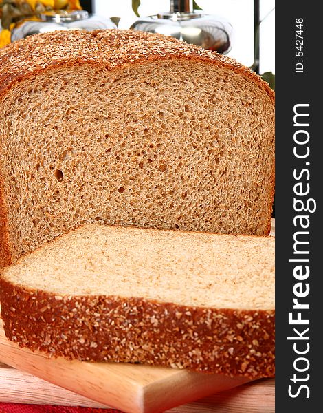 Whole wheat bread sliced on cutting board in kitchen or deli.